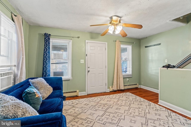 living room featuring a baseboard heating unit, a textured ceiling, a wealth of natural light, and wood-type flooring