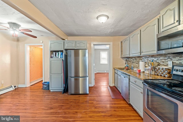 kitchen featuring hardwood / wood-style flooring, a baseboard radiator, and appliances with stainless steel finishes