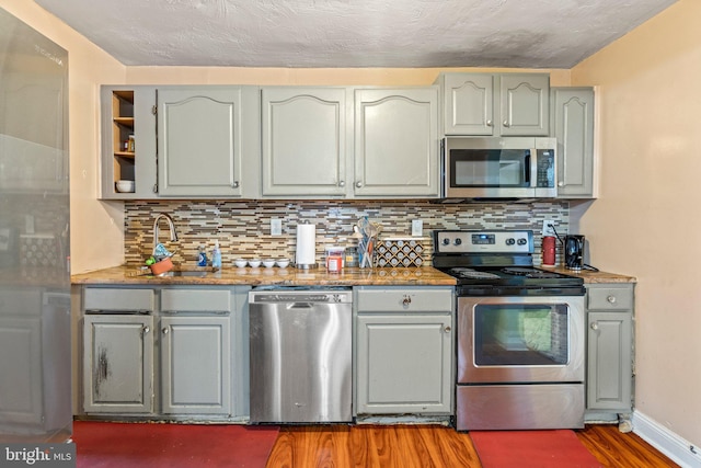 kitchen with gray cabinets, sink, decorative backsplash, hardwood / wood-style flooring, and stainless steel appliances