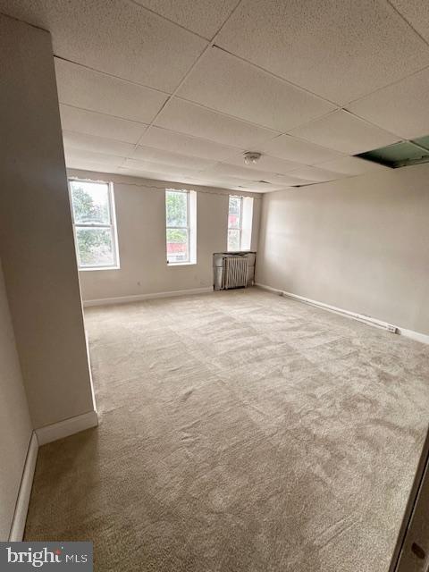 spare room with a paneled ceiling, baseboards, and carpet floors