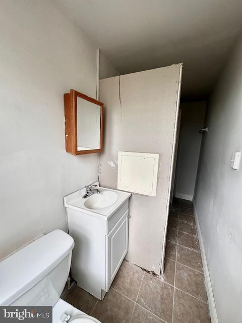 bathroom with toilet, tile patterned floors, and vanity