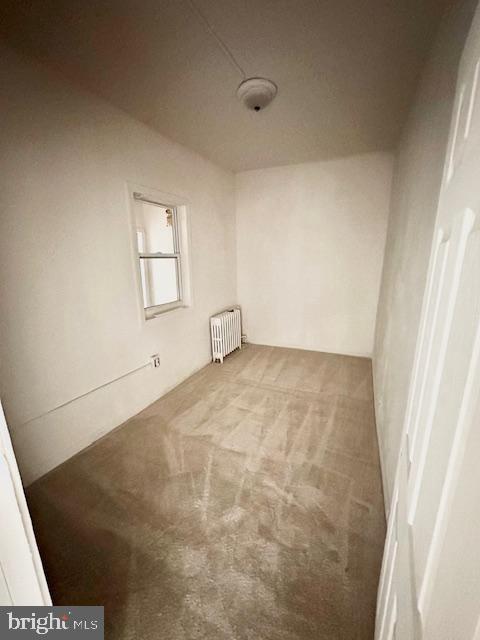 carpeted empty room featuring radiator heating unit