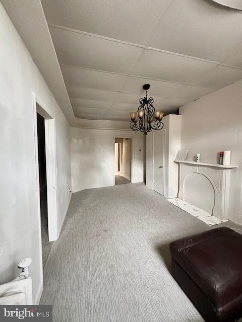 living room with carpet flooring, baseboards, a notable chandelier, and a paneled ceiling