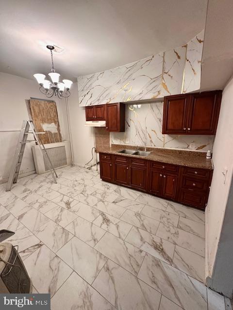 kitchen with hanging light fixtures, a sink, a notable chandelier, under cabinet range hood, and marble finish floor