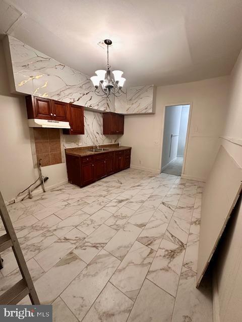 interior space featuring a sink, an inviting chandelier, and marble finish floor
