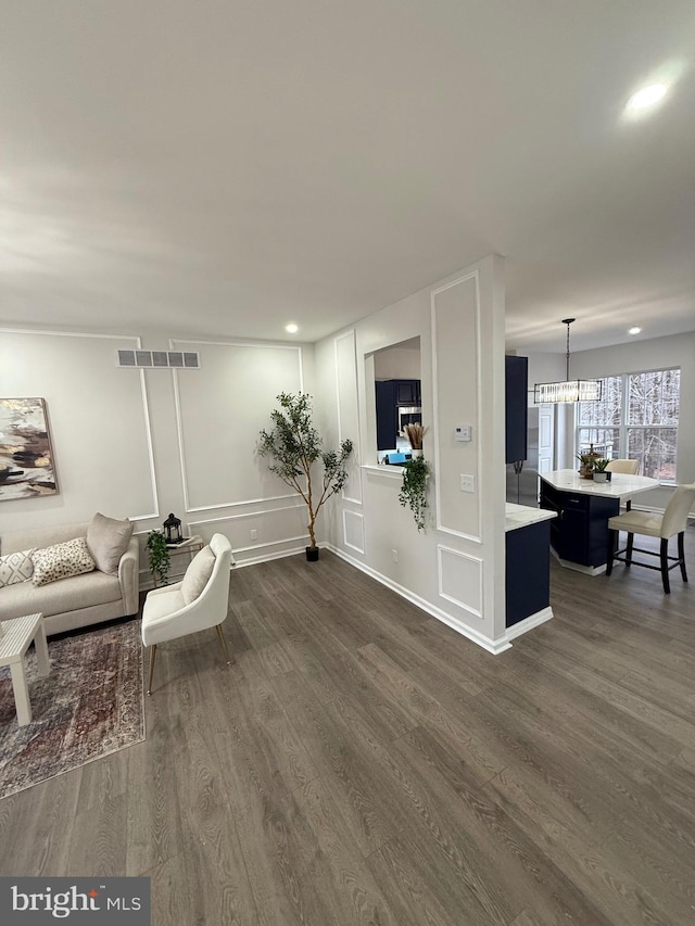 living room with an inviting chandelier and dark hardwood / wood-style flooring