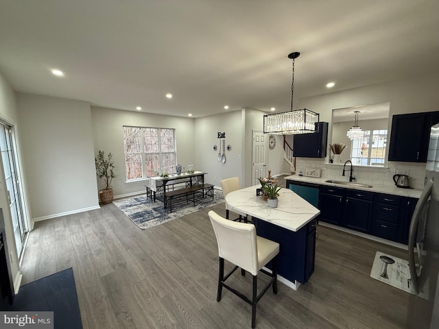 kitchen featuring sink, dark hardwood / wood-style flooring, a kitchen island, pendant lighting, and backsplash