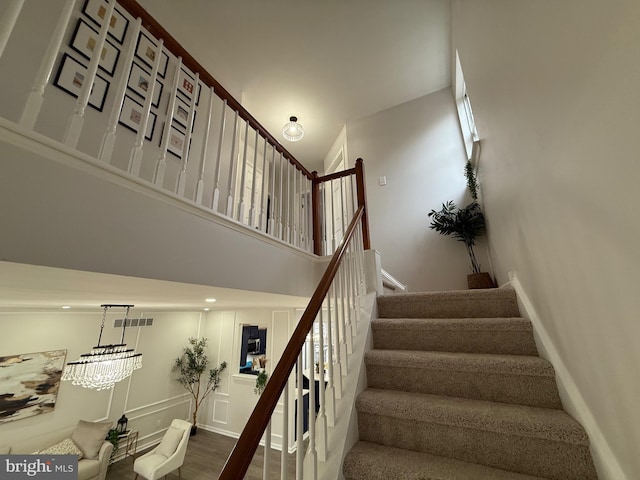 staircase with wood-type flooring and a towering ceiling