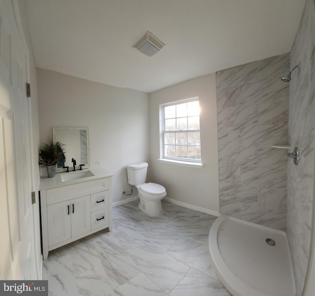 bathroom featuring vanity, a tile shower, and toilet