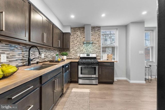 kitchen with wall chimney exhaust hood, sink, dark brown cabinets, appliances with stainless steel finishes, and decorative backsplash