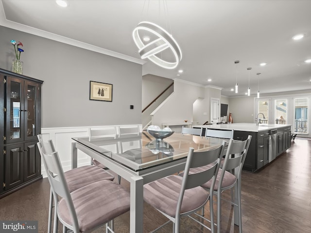 dining room with wainscoting, ornamental molding, dark wood-style flooring, and a chandelier