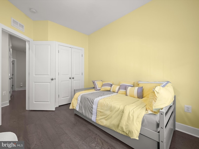 bedroom with wood finished floors, visible vents, a closet, and baseboards