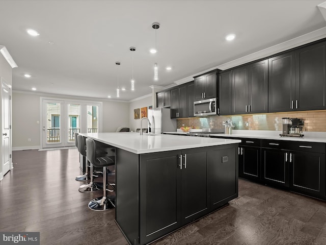 kitchen featuring a spacious island, ornamental molding, stainless steel appliances, and dark cabinets