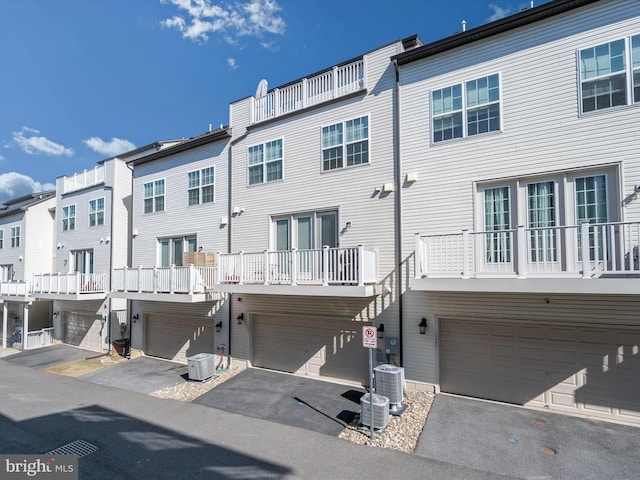 rear view of property featuring a garage, a residential view, central AC unit, and driveway