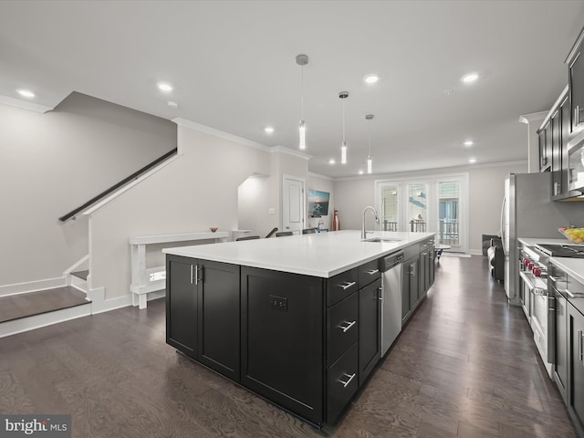 kitchen featuring a sink, light countertops, appliances with stainless steel finishes, dark cabinetry, and a kitchen island with sink