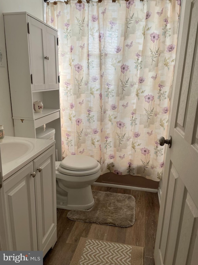 full bath with shower / tub combo with curtain, toilet, vanity, and wood finished floors