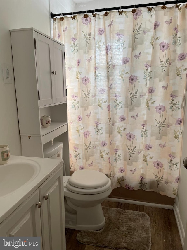 bathroom featuring shower / tub combo with curtain, toilet, vanity, and wood finished floors