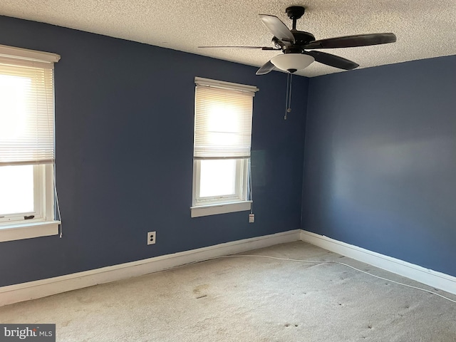 carpeted spare room featuring baseboards, a textured ceiling, and ceiling fan