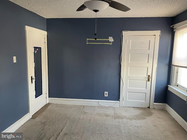 carpeted spare room with a wealth of natural light, baseboards, and a textured ceiling