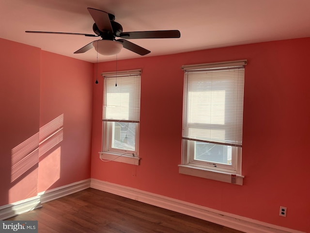 empty room featuring a ceiling fan, baseboards, and dark wood-style flooring