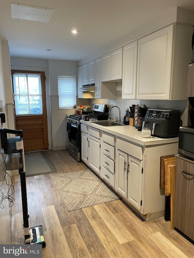 kitchen with light wood-style flooring, white cabinets, appliances with stainless steel finishes, and a sink