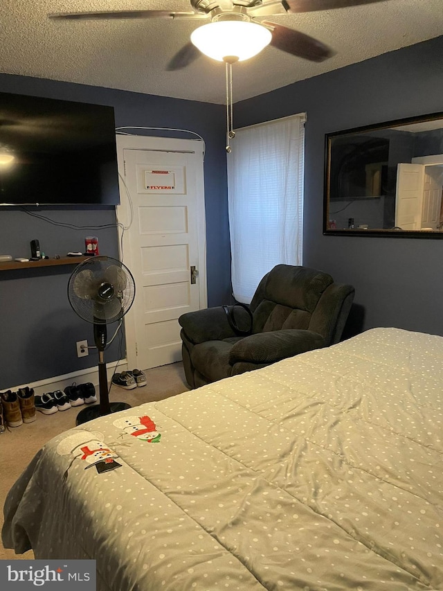 bedroom with a textured ceiling, a ceiling fan, and carpet