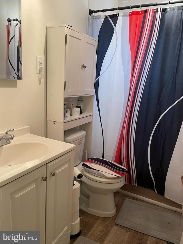 bathroom featuring a shower with shower curtain, toilet, vanity, and wood finished floors