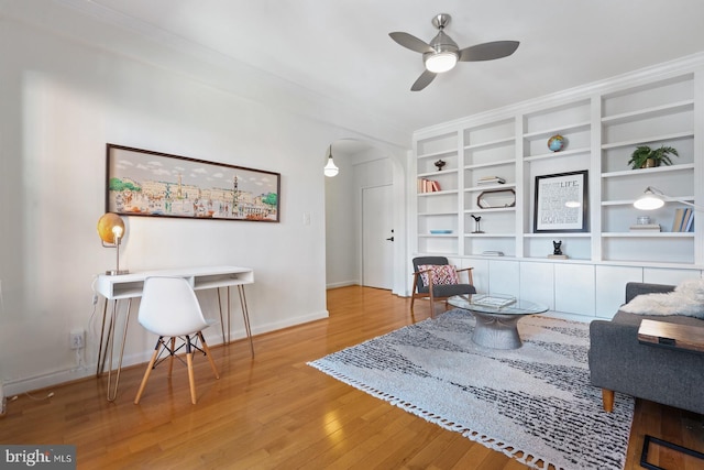 living room with ceiling fan, ornamental molding, light hardwood / wood-style floors, and built in shelves