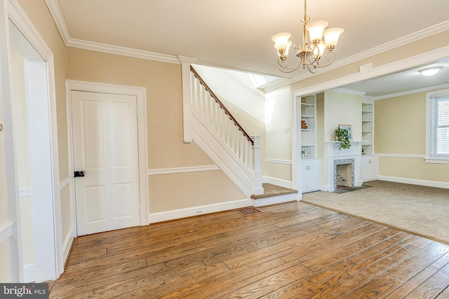 foyer entrance with wood-type flooring, ornamental molding, and a chandelier