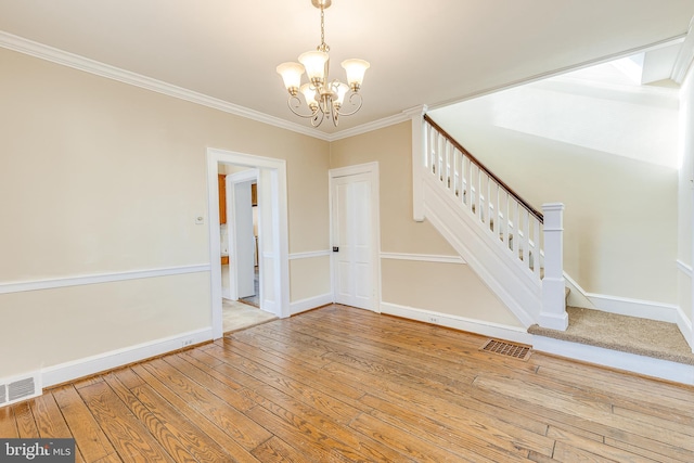 unfurnished room featuring ornamental molding, wood-type flooring, and a notable chandelier