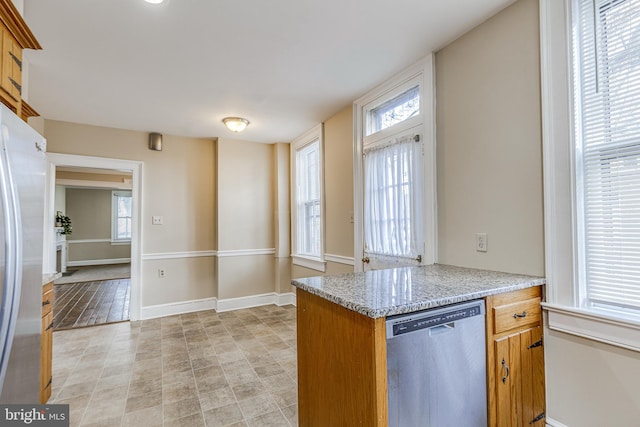 kitchen with appliances with stainless steel finishes, light stone countertops, and kitchen peninsula