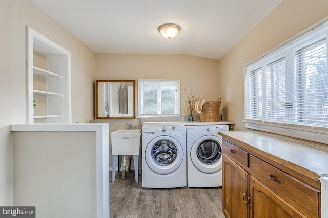 laundry area with cabinets, washing machine and clothes dryer, and light hardwood / wood-style floors