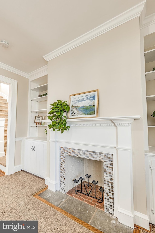 room details with ornamental molding, carpet floors, a fireplace, and built in shelves