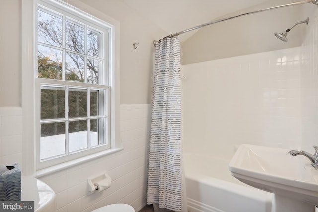 full bathroom with tile walls, sink, shower / bath combination with curtain, and toilet