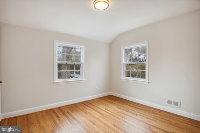 empty room featuring vaulted ceiling and light hardwood / wood-style floors