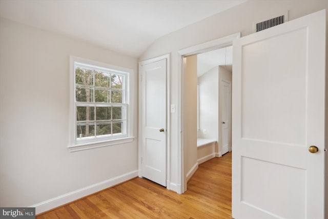 hall featuring wood-type flooring and vaulted ceiling