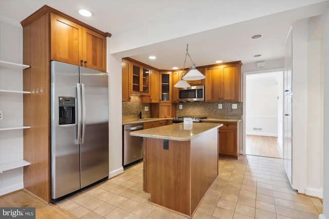 kitchen with hanging light fixtures, stainless steel appliances, a center island, light stone counters, and tasteful backsplash