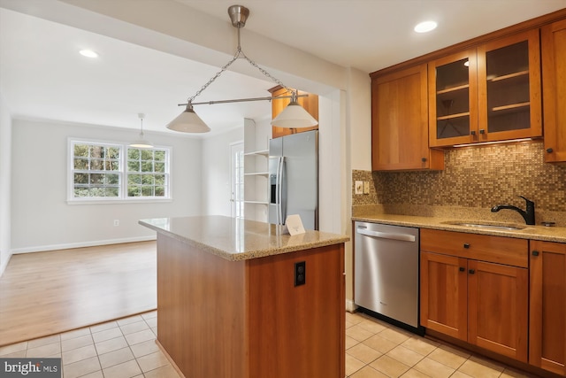 kitchen featuring a kitchen island, sink, hanging light fixtures, light stone counters, and stainless steel appliances