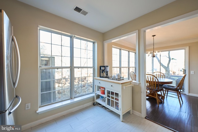 dining space with a chandelier, light wood finished floors, visible vents, and baseboards