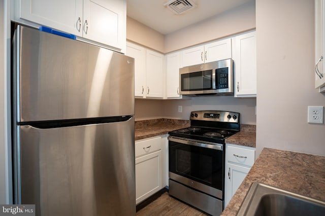 kitchen featuring dark hardwood / wood-style flooring, white cabinets, and appliances with stainless steel finishes