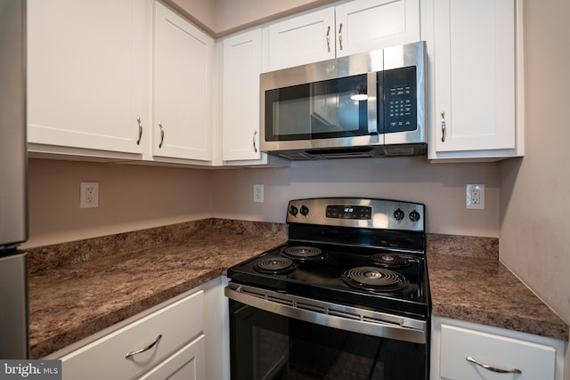 kitchen featuring range with electric cooktop, dark stone countertops, and white cabinets