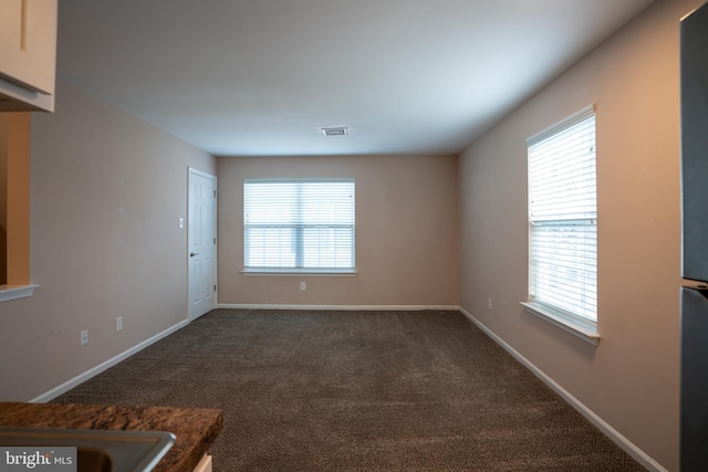 spare room featuring a healthy amount of sunlight and dark colored carpet