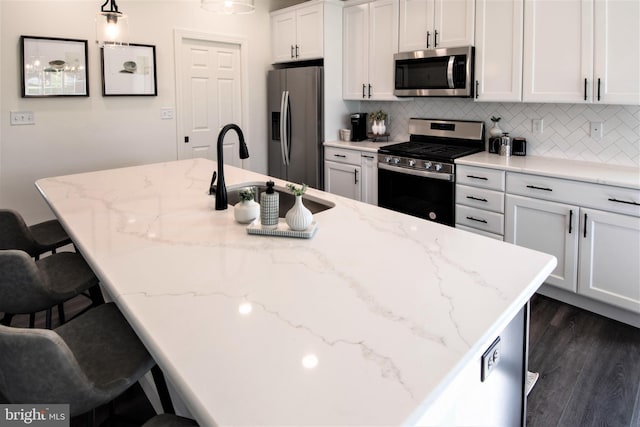 kitchen with decorative light fixtures, a kitchen breakfast bar, white cabinets, and appliances with stainless steel finishes