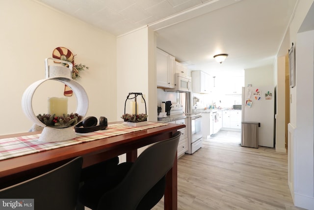 kitchen featuring white appliances, light hardwood / wood-style floors, and white cabinets