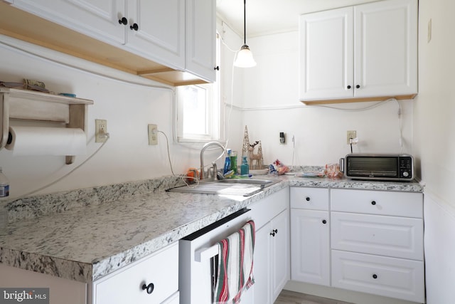 kitchen featuring pendant lighting, sink, stainless steel dishwasher, and white cabinets