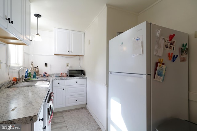 kitchen with sink, white cabinetry, hanging light fixtures, white refrigerator, and light stone countertops