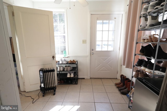 doorway to outside featuring radiator heating unit, a wealth of natural light, ceiling fan, and light tile patterned flooring