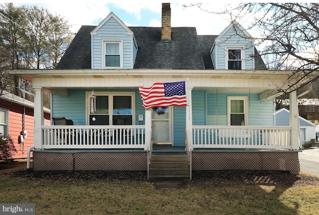 new england style home featuring a porch and a front lawn