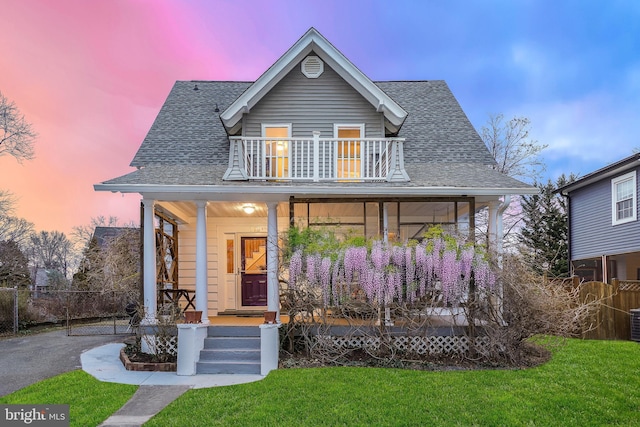 view of front of property featuring cooling unit, a porch, a yard, and a balcony