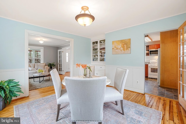 dining area with hardwood / wood-style flooring, crown molding, and built in shelves